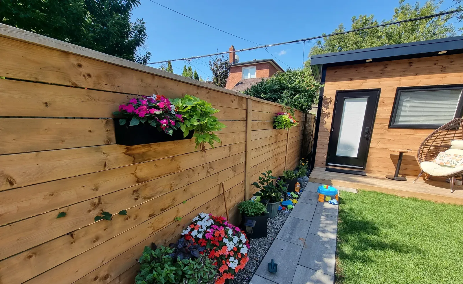 Horizontal cedar fence with hanging planters beside a landscaped side yard
