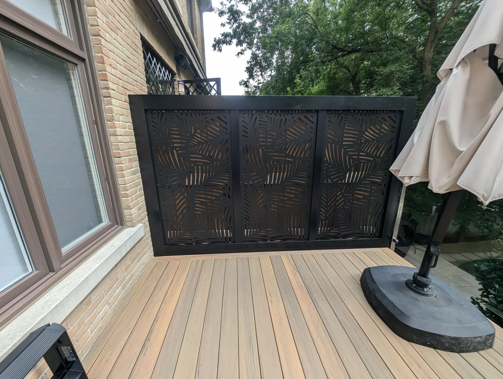 Composite deck with mixed-tone boards and decorative black privacy panel