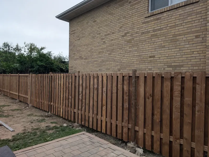 Board on board privacy fence freshly installed along a property line