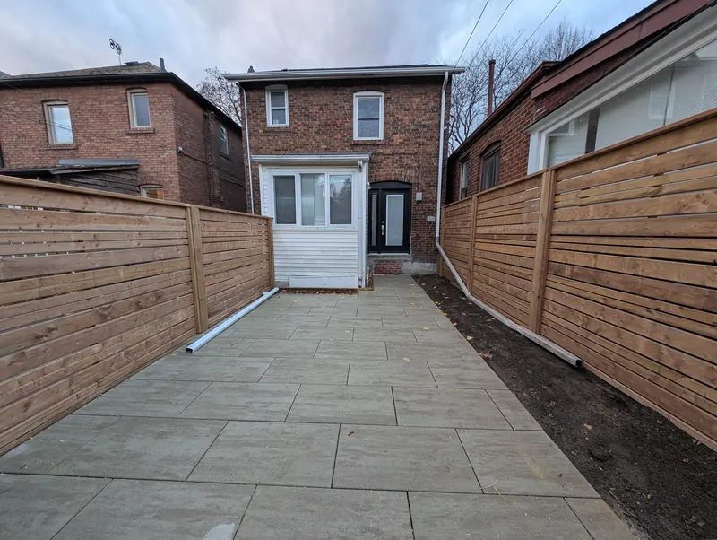 Matching horizontal cedar fences on both sides of a paved side yard walkway