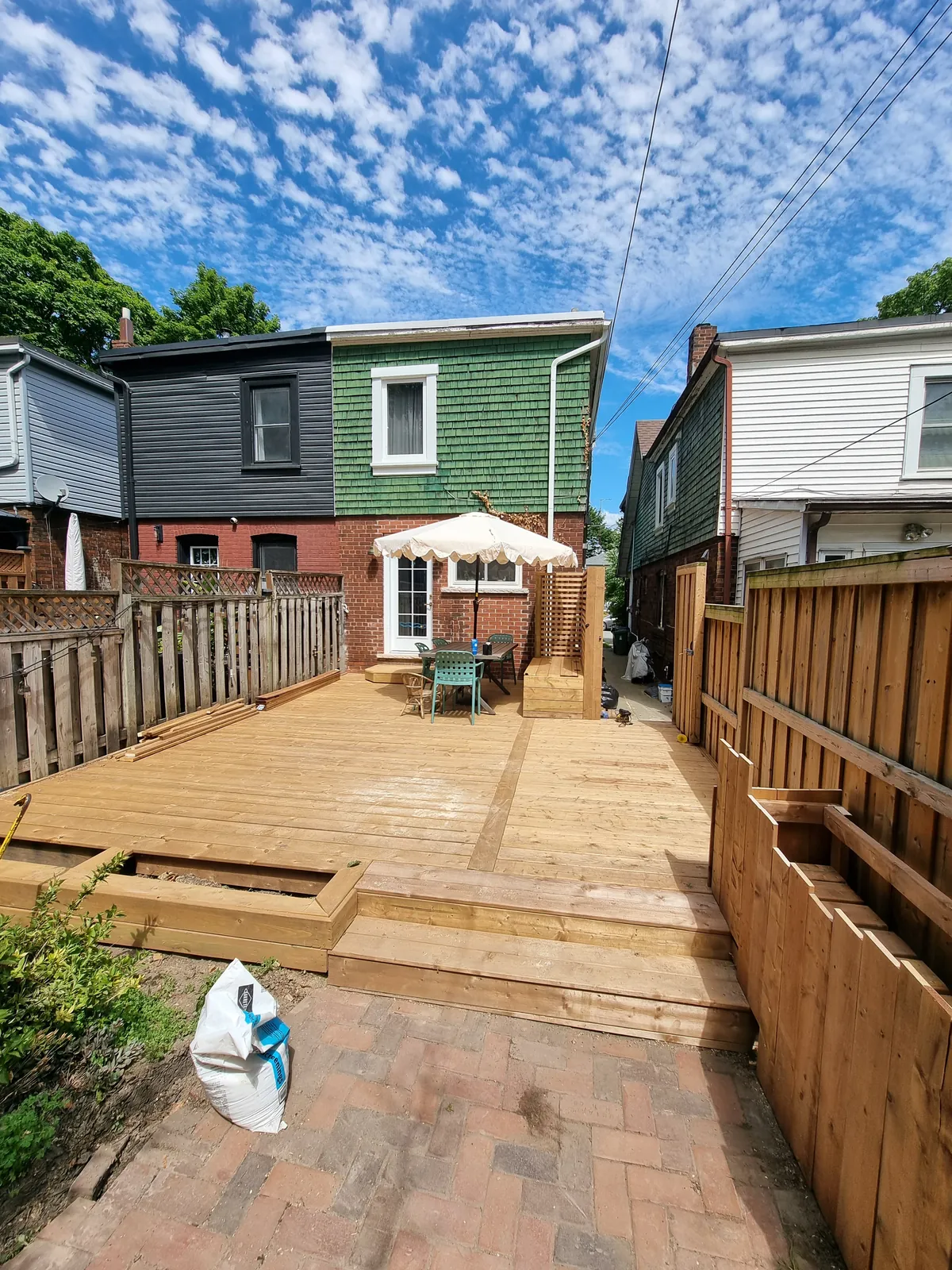 Wide finished wood deck across a Toronto backyard under a blue sky