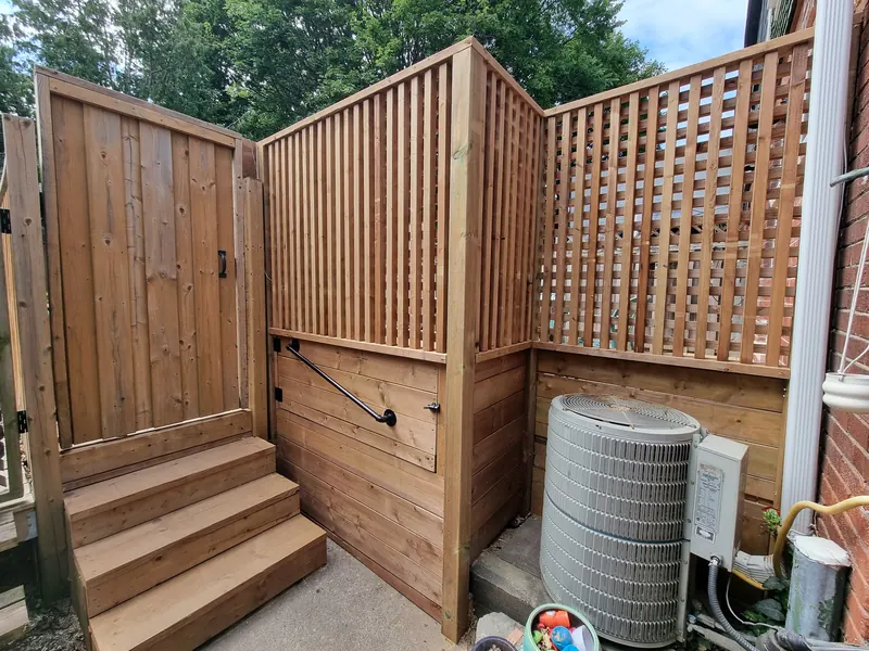 Custom cedar privacy screen with gate and steps concealing utility equipment
